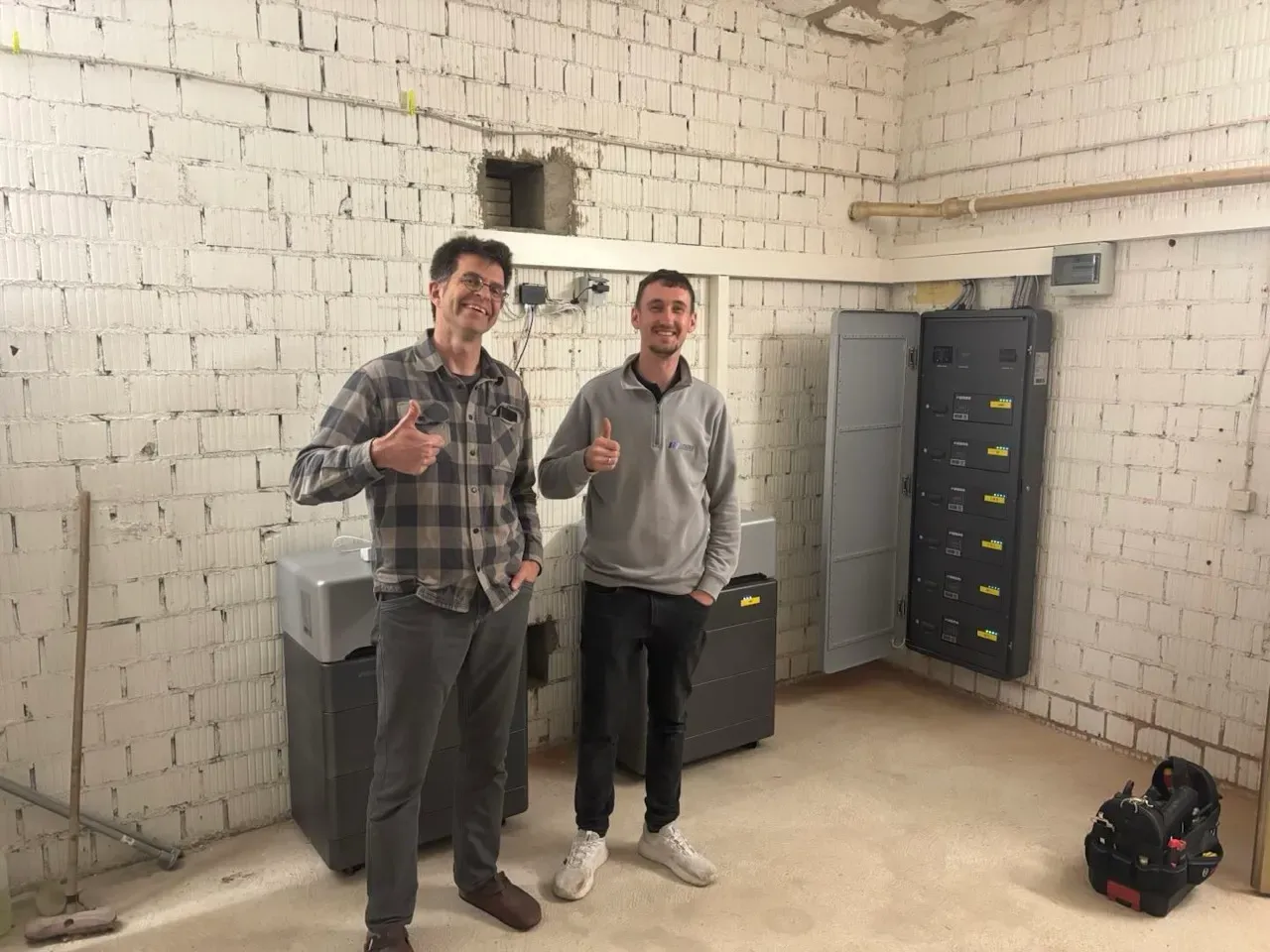 Techniker präsentieren installierte WEESS Batteriespeicher und Powertower Energieverteilungssystem im Technikraum