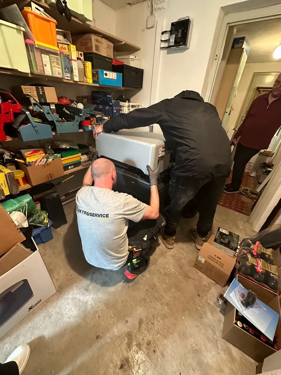 Technicians installing battery storage units in the utility room of a residential building